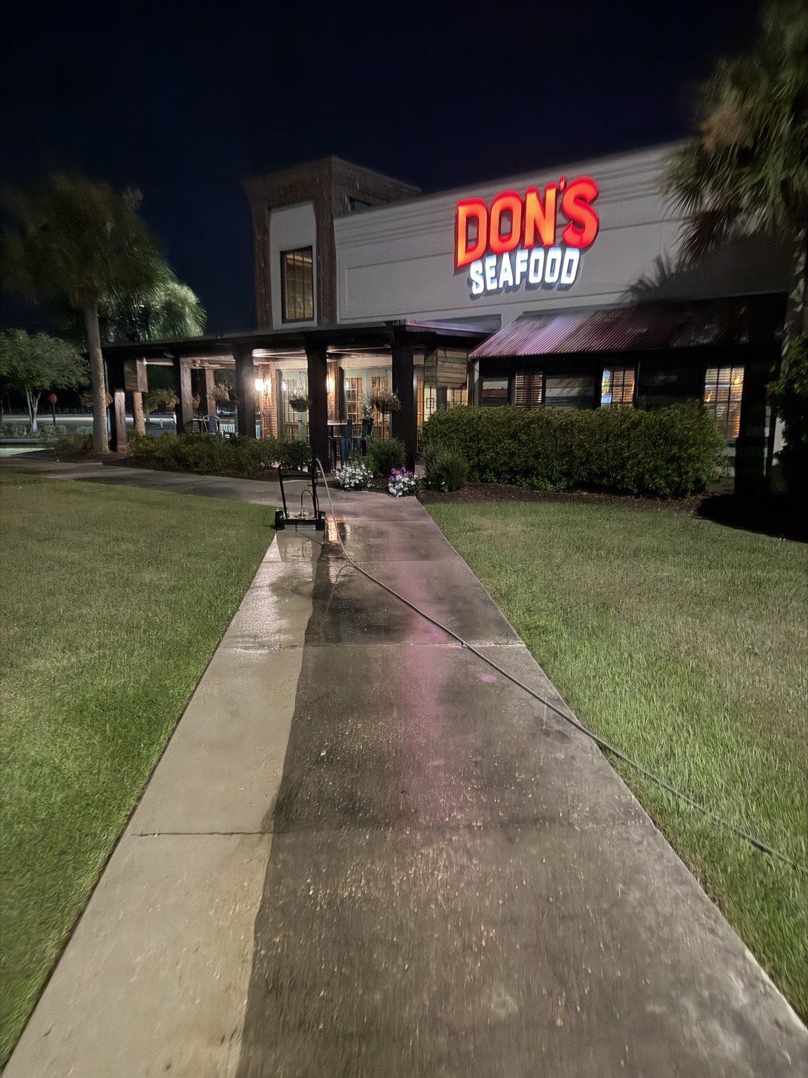 Commercial walkway being cleaned at night outside Don's Seafood